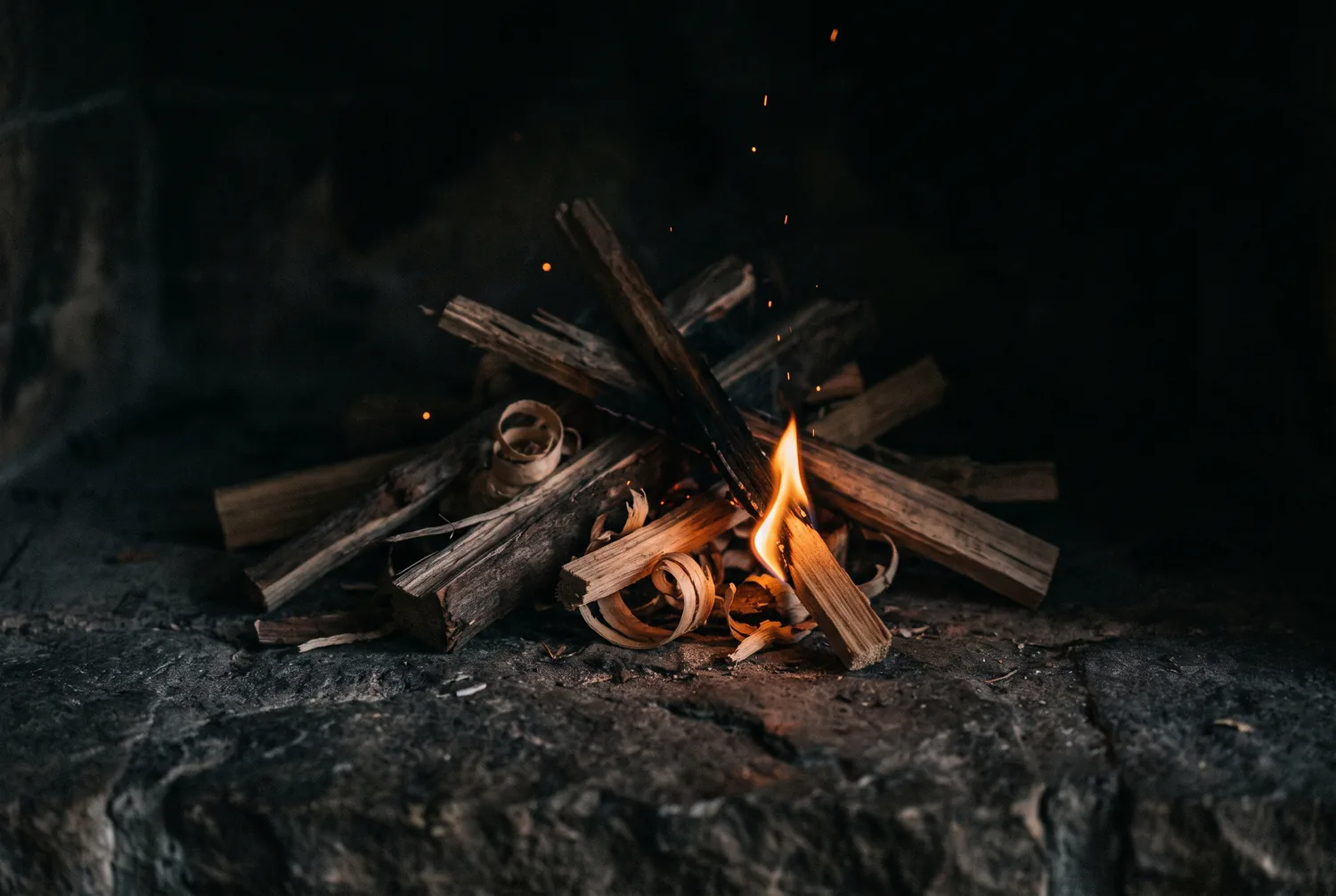 Anzündholz fängt Feuer auf einem dunklen Steinherd